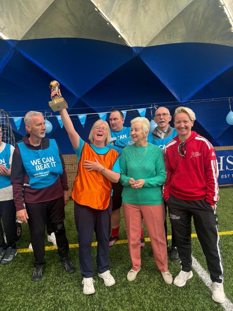 The winners of a walking football match with their trophy