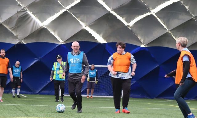 Walking Football 2026 People with blue and orange bibs playing walking football